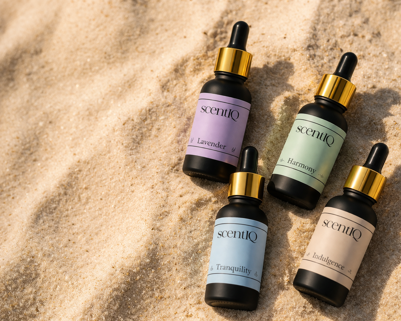 Four scentiQ essential oil dropper bottles on a beach