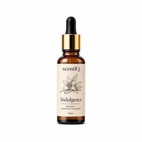 A 20ml amber glass dropper bottle of scentIQ 'Indulgence' essential oil blend, featuring a cream-colored label with a black ink botanical illustration and a shiny gold collar, set against a plain white background.